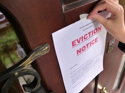 image of a hand sticking an eviction notice to a front door or a home.