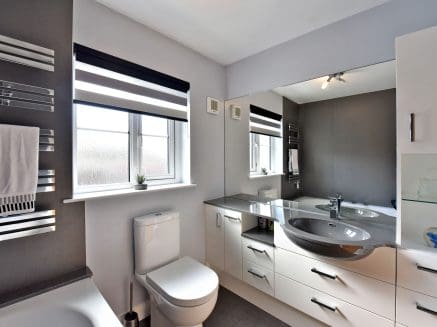 image of a grey built in bathroom with cupbioards highlighting built in storage.