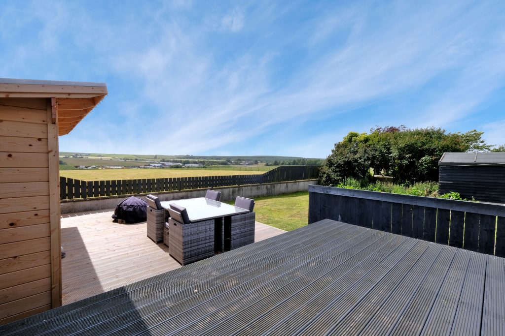 sunny view of back garden with decking and outdoor seating area 